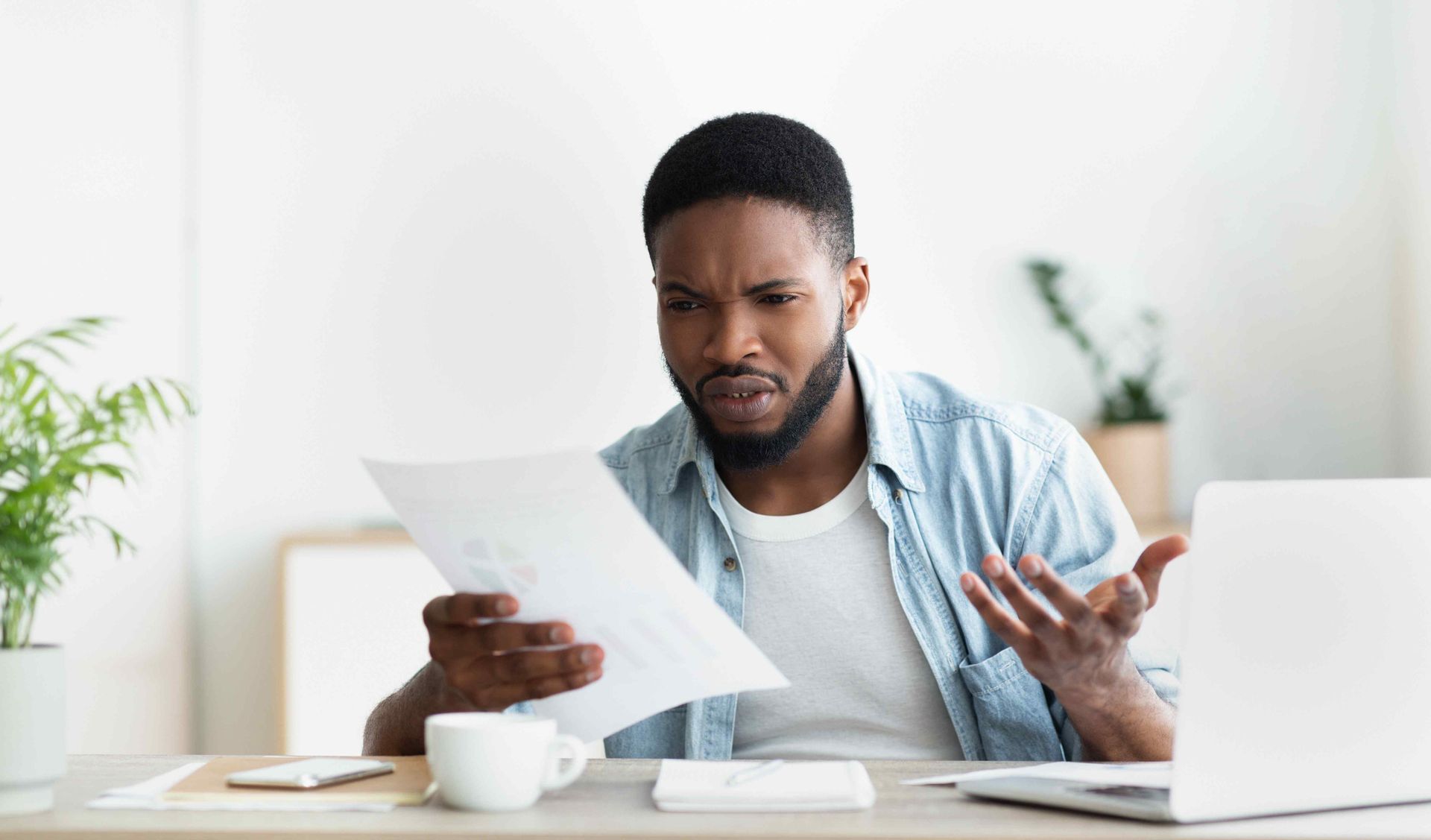 Business owner comparing a printed report against figures on his laptop