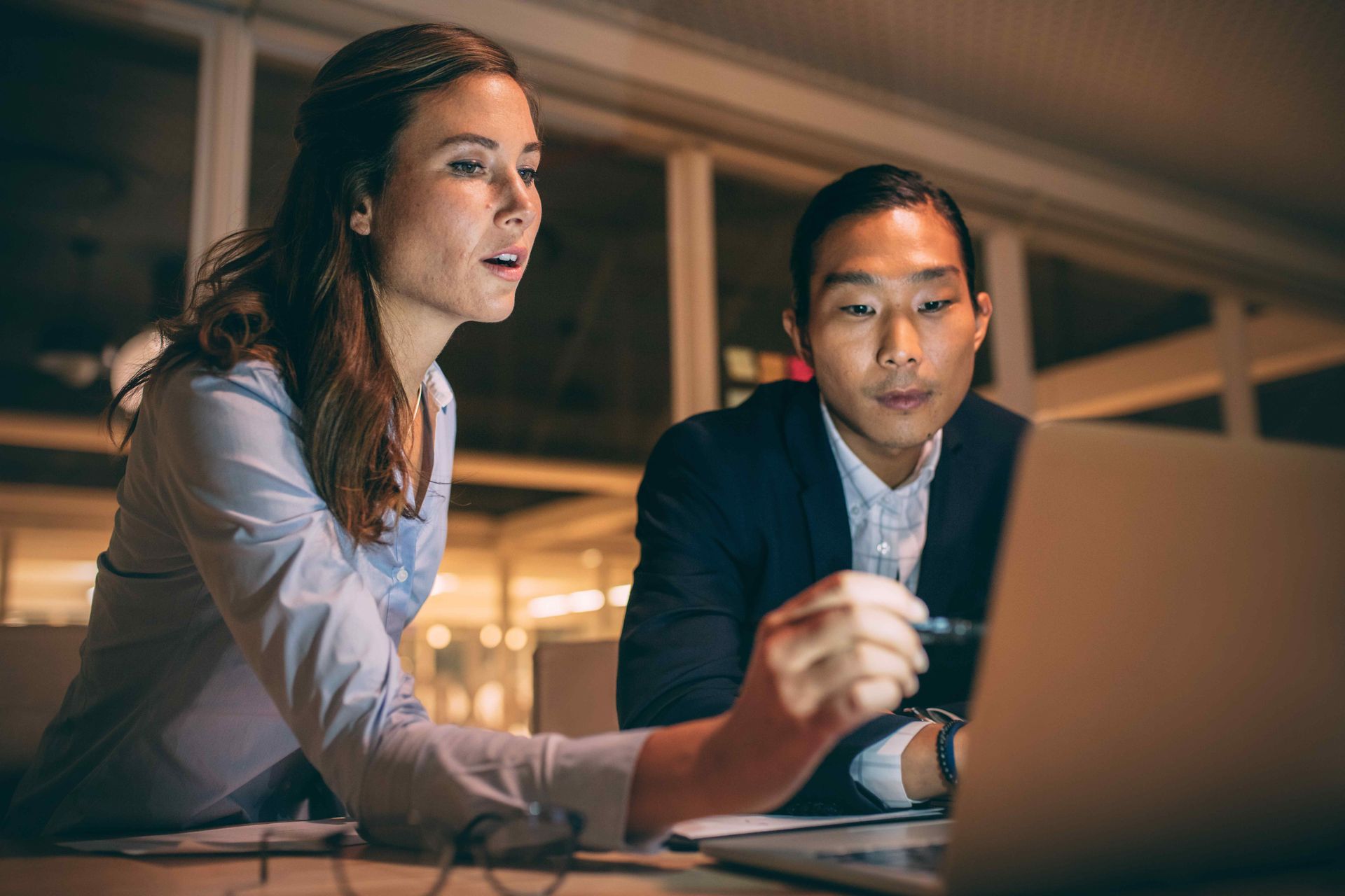 Two colleagues reviewing financial statements together on a laptop